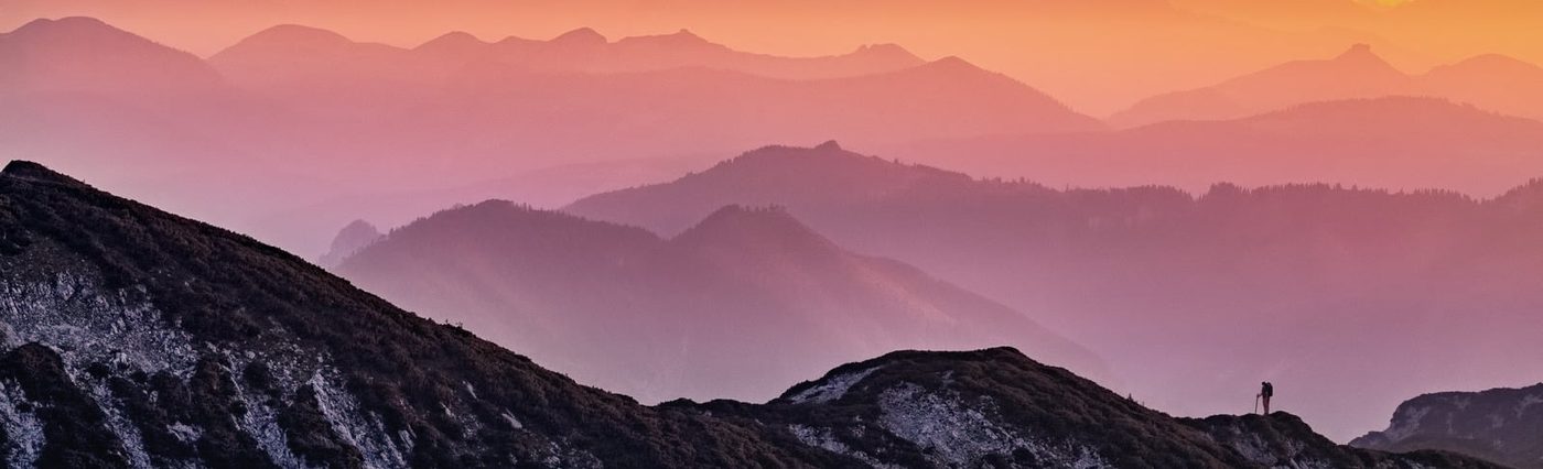 Mountain ridge at sunset with hiker silhouette